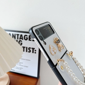 Detail showing white textured case for Samsung Galaxy Z Flip with pearl strap and bear charm