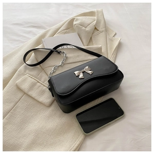 Detail of black crossbody bag featuring a silver butterfly clasp and chain strap
