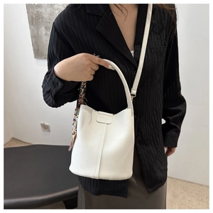 Close-up of white bucket bag with pebble leather texture and fashion silk scarf detail