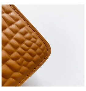 Macro view of brown crocodile embossed leather with neat stitching on a small square bag
