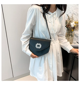 Détail du sac bandoulière en cuir noir avec une boucle carrée en strass scintillants
