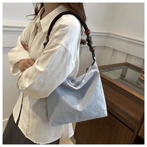 Detail of light blue velvet shoulder bag with wooden bead and braided rope strap