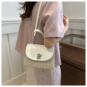 Detail of a straw woven handbag featuring white leather flap and silver keyhole twist lock