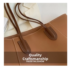 Detail of brown leather tote showing fine texture and contrast beige stitching