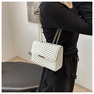 Detail of white quilted handbag with golden chain strap and V-pattern stitching