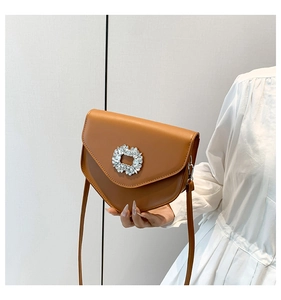 Vue détaillée du sac bandoulière en cuir caramel avec une boucle en strass brillante