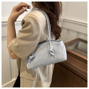 Détail du sac sous le bras plissé bleu clair avec bandoulière à nœud et logo doré