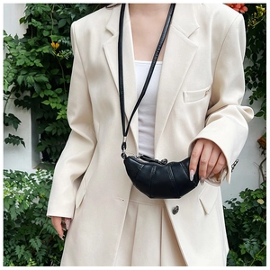 Close-up of a mini black croissant shoulder bag made of sleek synthetic leather