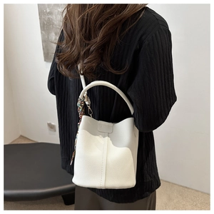 Detail of white lychee leather bucket bag with a colorful floral silk scarf decoration