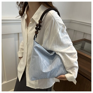 Detail of light blue pleated velvet tote bag with artisanal wooden bead shoulder strap