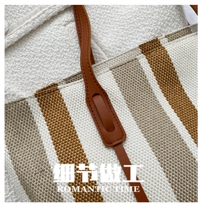 Detail shot of sturdy brown leather handle stitching on striped woven tote bag