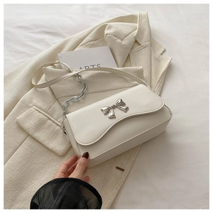 Detail of creamy white crossbody bag with silver butterfly buckle and chain strap