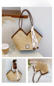 Detail of straw tote bag with brown leather trim and decorative branded white ribbon