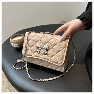 Detailed view of apricot quilted chain bag with silver metal bow and luxury texture