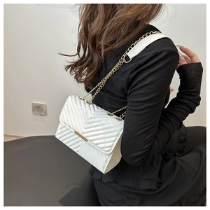 Detail showing white V-shaped quilted leather texture and golden metal chain strap on bag