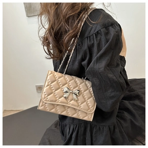 Quilted crossbody bag with silver bow detail shown on shoulder from a back side view