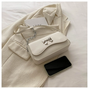 Detailed macro view of the cream white crossbody bag with a silver butterfly bow clasp
