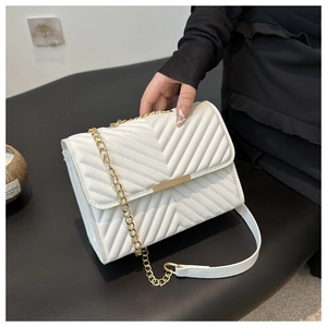 Close-up of white quilted leather bag with V-stitch patterns and gold chain strap