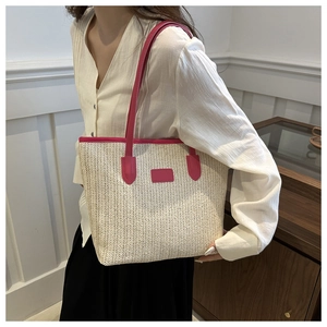 Detail of a large straw tote bag with vibrant pink leather straps and a woven design
