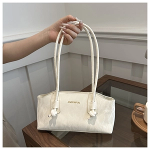 Détail du sac crème en cuir plissé avec bandoulière à nœud au design minimaliste
