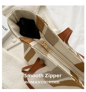 Detailed macro view of the smooth gold metal zipper closure on striped canvas tote bag
