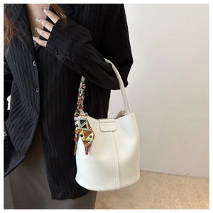 Makroaufnahme der weißen Beuteltasche aus genarbtem Leder mit dekorativem buntem Seidenschal