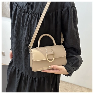 Detail of elegant beige leather handbag featuring a prominent gold D-shaped metal buckle