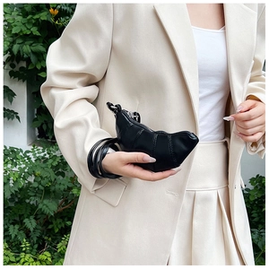 Detail of a mini black leather croissant bag with pleated texture and thin strap