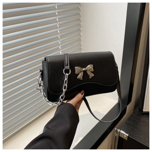 Detail of black leather square bag with silver metal bow clasp and thick chain strap