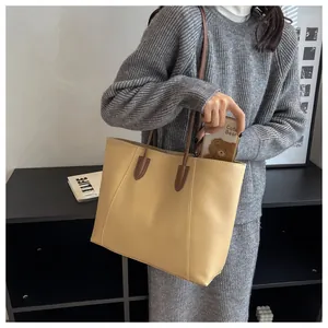 Detailed side view of large beige leather tote bag with dark brown straps for daily use