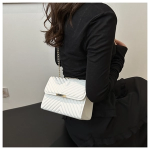 Close-up of white chevron quilted flap bag with gold rectangular clasp and chain strap