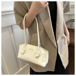 Gros plan sur le sac crème avec texture plissée et détail de nœud sur la bandoulière
