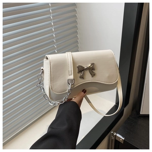Detail of cream crossbody bag featuring a silver butterfly buckle and leather strap