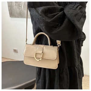 Dettaglio della borsa a tracolla beige vintage con fibbia metallica dorata a U su pelle