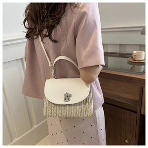 Detail of woven straw crossbody bag with white leather flap and silver turn-lock clasp