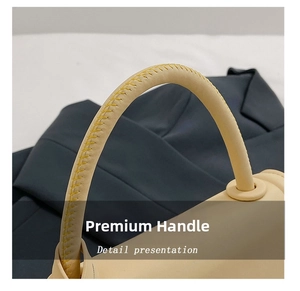 Close-up of cream leather handle with bright yellow stitching detail on a handbag