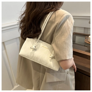 Détail d'un sac cabas en cuir PU blanc avec nœud décoratif et logo doré chic