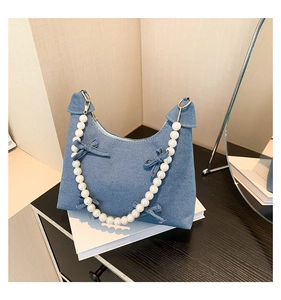 Close-up of blue denim tote bag featuring large pearl handle and cute bow accents