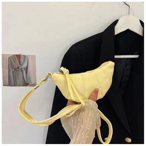 Detailed view of pale yellow croissant bag with vertical stitching and thin strap