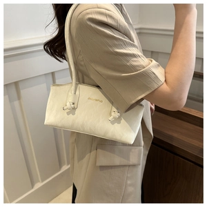 Détail du sac à épaule blanc en cuir avec nœud sur la bandoulière et logo doré