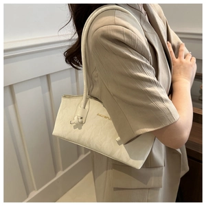 Détail d'un sac sous les bras en cuir texturé blanc cassé avec logo doré sur mannequin