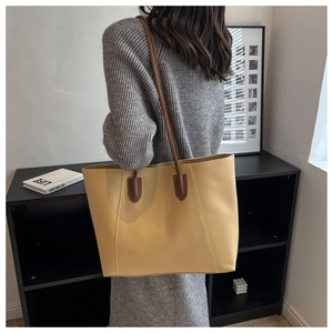 Detail of a ginger yellow large tote bag with brown leather straps for daily commute