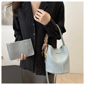 Detail der hellblauen Beuteltasche mit Lederstruktur und bedrucktem Seidenschal-Accessoire