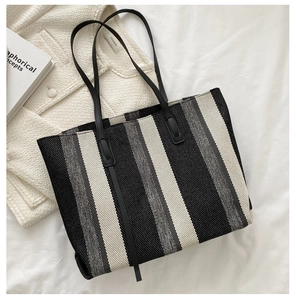 Close-up of vertical striped large tote bag with black leather straps on white fabric
