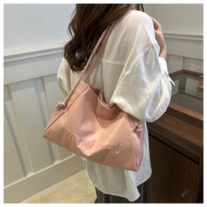Dettaglio borsa tote rosa in pelle morbida con scritte WGONGZHU a rilievo e nodo decorativo