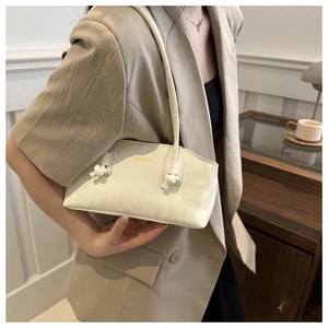 Détail du sac sous l'aisselle blanc crème avec sangle à nœud et logo doré sur cuir PU fin
