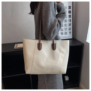 Detail of minimalist cream tote bag with brown straps shown on shoulder for capacity