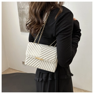 Detail of white V-quilted faux leather bag with gold chain strap and metal lock closure