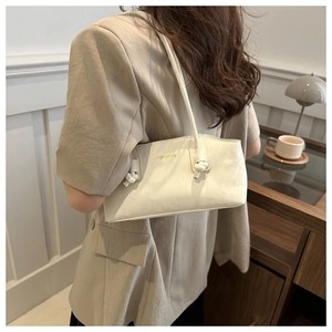 Détail du sac seau beige crème avec bandoulières nouées et logo doré minimaliste