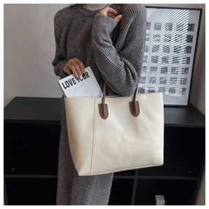 Spacious off-white tote bag with brown straps shown being worn on a shoulder